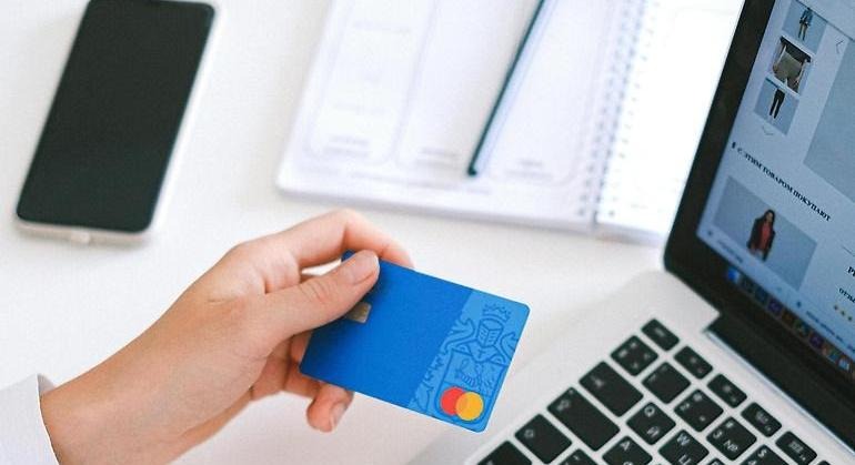 En person håller i ett bankkort för att betala internetköp.