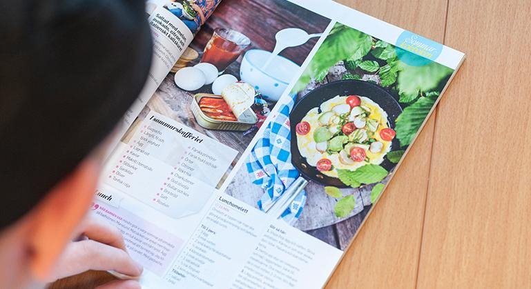 En elev sitter och tittar i en mattidning med recept.