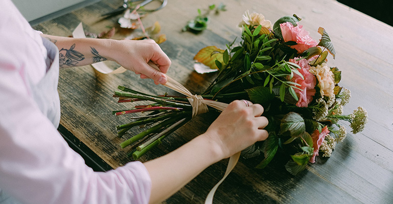 En florist knyter ett band kring skaften på en bukett.